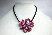 Front view of necklace showing deep pink shell flower pendant on black leather cord