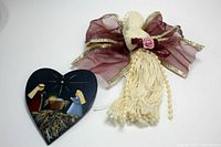 Heart-shaped brooch painted with nativity scene including Mary, Joseph, and baby Jesus in manger; highlights pin size and painted detail on dark blue heart background.