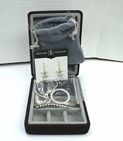 Photo of the jewellery travelling case containing rhinestone earrings, a stretchy bracelet, and soft grey pouch inside the case.