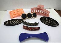 Full view of nine assorted hair clips including claw clip, scrunchie, velvet and tortoiseshell style clips laid out on white backdrop.