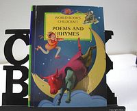 Front cover of the Childcraft Poems and Rhymes book showing colorful illustration of figure riding red bull on a crescent moon.