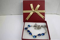 Silver-tone necklace laid in a red gift box with gold ribbon.