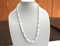 Front view of the 28-inch white necklace with gold spacer beads and screw closure on display bust.