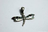Top down view of dragonfly pendant showing two pairs of abalone inlay wings in sterling silver frame with bail.