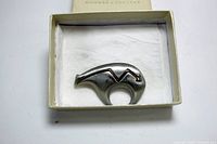 Top view of silver-toned polar bear brooch in white gift box with fabric lining showing the front of the brooch.