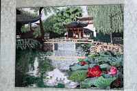 Close-up view of the entire embroidery showing a Japanese garden scene with bridge, pond, teahouses and lotus flowers.