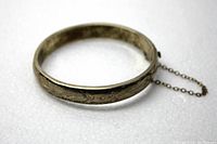 Photo showing the full ronde band bracelet made of sterling silver with visible floral pattern etching and attached safety chain to secure clasp.