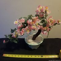 Front view of the vintage Chinese jade bonsai tree with blossoms and green leaves in a celadon pot, tape measure below for size reference.