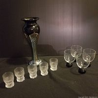 All items arranged: vase on left, shot glasses front center, stem glasses on right