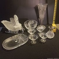 Full lot displayed against black backdrop showing all glass pieces including the swan figurine on sleigh, tall vase, pedestal bowl with swan motif, four etched glasses, small cut-glass vase, and etched serving tray.