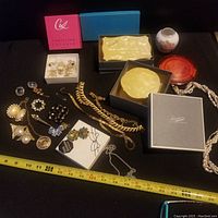 Lot overview showing jewelry pieces and containers on black surface