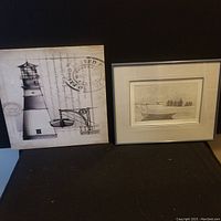 Framed John Neville signed etching titled 'Gathering in the Fog' next to nautical-themed canvas art showing a lighthouse and boat