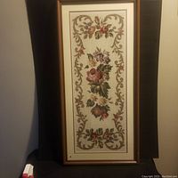 Full view of the large framed needlepoint featuring floral designs and scrollwork in a wooden frame.