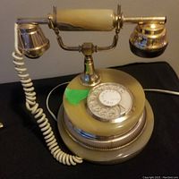 Overall view of the vintage rotary phone showing marble and silver finish with handset and coiled cord.