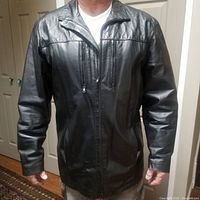 Front view of the men's black leather coat showing zippers and collar.