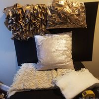 Two photos of decorative pillow covers and blankets arranged on a black backdrop and floor for display, showing condition and detail of each item