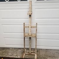 Full view of the vintage wooden easel displaying its structure and worn white paint.