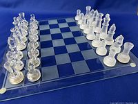 Full shot of chess set on glass board showing clear pieces on one side and frosted pieces on the other.