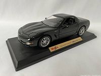 Front angle view of the Maisto Chevrolet Corvette 2001 black model car on display base with nameplate.