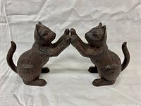 Front view of the pair of metal cat bookends side by side, showing them facing each other with paws touching.