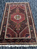 Full top-down image showing the handmade Persian wool rug's colorful geometric medallion design and bordered edges with fringe.