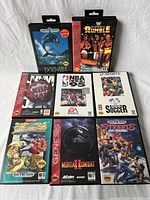Eight Sega Genesis game cartridges and cases arranged in two rows. Titles visible are Ecco the Dolphin, Royal Rumble, NBA Jam, NBA Live 95, FIFA International Soccer, Street Fighter II, Mortal Kombat II, Streets of Rage 2.