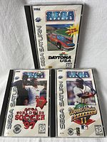 Front covers of Daytona USA, Sega Worldwide Soccer 97, and World Series Baseball II Sega Saturn games.