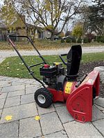 Front right angle view of red MTD Yard Machines snow blower with engine, chute, handlebars, tires visible.