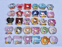 Photo shows full collection of 30 colorful lenticular Hello Kitty magnets from 1994-2004 arranged in rows on plain background. Shapes include hearts, flowers, stars, and squares with year markings and cute Hello Kitty images.