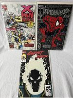 Three vintage Marvel comics displayed upright: X-Men Unlimited No. 1, Spider-Man black and white cover 'Torment', and Ghost Rider with flaming skull cover.