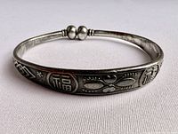 Front side view of the silver Asian bracelet showing the raised Chinese characters and prosperity symbol along the band.