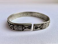 Front view showing Chinese double happiness characters in raised silver on oxidized textured background on open cuff ends