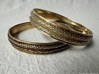 Two vintage silver bangles stacked together showing filigree pattern and aged patina.