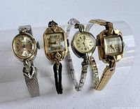 Four vintage cocktail wristwatches shown on clear display stand, front view.