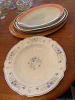 Stack of five oval serving platters showing varied sizes and colors, plus visible chips and wear.