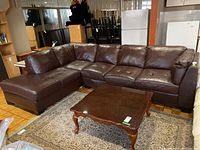 Full view of brown leather two-piece sectional sofa with right-facing chaise in a room setting