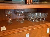 Shelf with 8 clear wineglasses and 16 short-stemmed goblets with decorative cut glass bases.