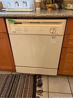 Front view of the white Kenmore dishwasher fitted under kitchen counter, showing control panel and front door.
