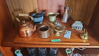 Lot shown on wooden shelf with various kettles, mortar and pestle, brass items, trinket box, lighter