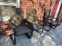 Front angled view of three patio chairs showing newish metal frames and mesh fabric seats and backs with some shadowing from sunlight.