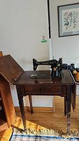 Full view of the vintage Singer sewing machine on its wooden cabinet with foldable top closed.