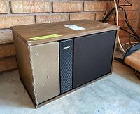 Pair of Bose 301 Series 301 stereo speakers showing one speaker with torn beige fabric grill and wood casing with some wear.