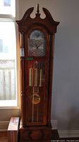 Full-height front view of oak case clock showing overall appearance and proportions