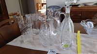 Wide view of crystal and glass items on table including vases, pitcher, and wine carafe