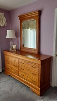 Front view of cherry wood dresser with matching mirror in bedroom setting