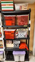 Black shelving unit holding multiple plastic bins and boxes containing holiday decorations