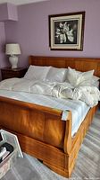 Front-angle view of assembled cherry wood king-size bed with white bedding and mattress
