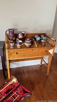 Wooden table with drawer seen from the front with various ceramic pitcher and cup items on top (not included in sale).
