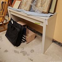 Side view of white side table with glass top showing the length and height against basement wall.