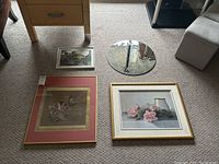 Four items on floor including three framed artworks and one round mirror